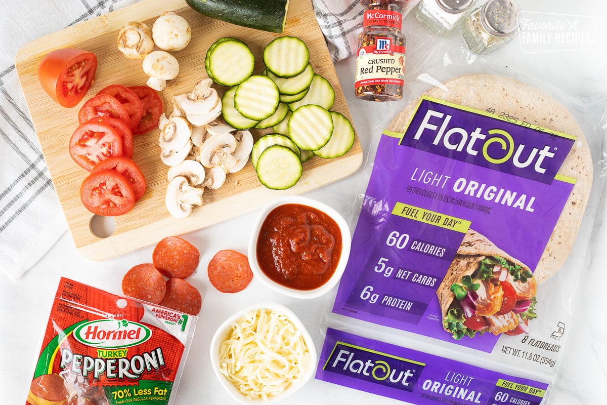 Ingredients for Healthy Pizza including Flat Out bread, tomatoes, mushrooms, zucchini, pizza sauce, turkey pepperoni, mozzarella cheese, crushed red pepper, salt and pepper.