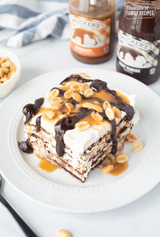 Ice Cream Sandwich Cake slice with hot fudge, caramel drizzling off the sides and peanuts.