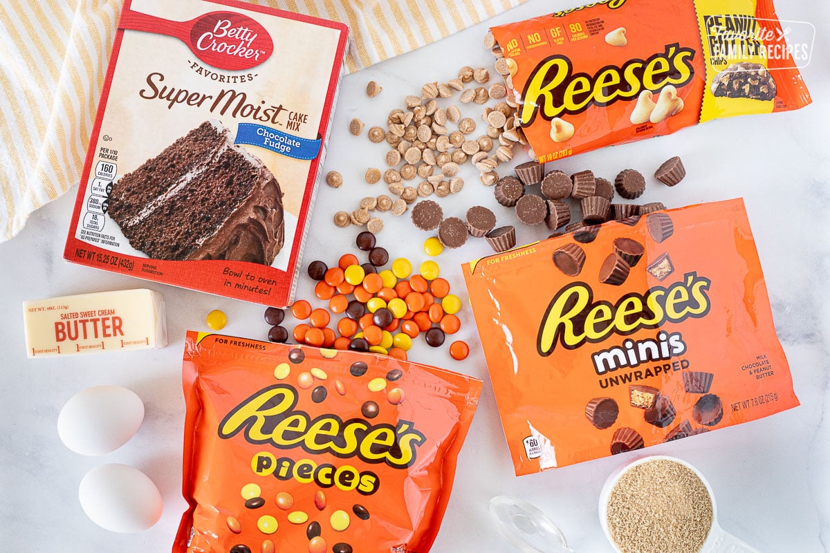 Ingredients for Reeses Pieces Cookies including Reese's Pieces, Reese's minis, Reese's peanut butter chips, Chocolate cake mix, butter, eggs, brown sugar and water.