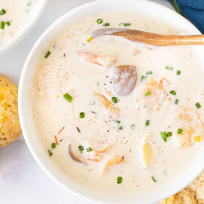 Large bowl of Seafood Chowder with a spoon. Garnished with green onions.