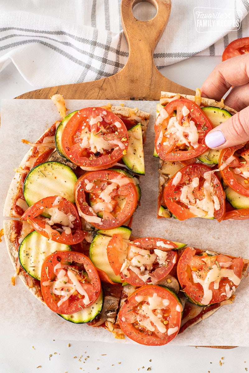 Hand picking up a slice of Healthy Pizza.