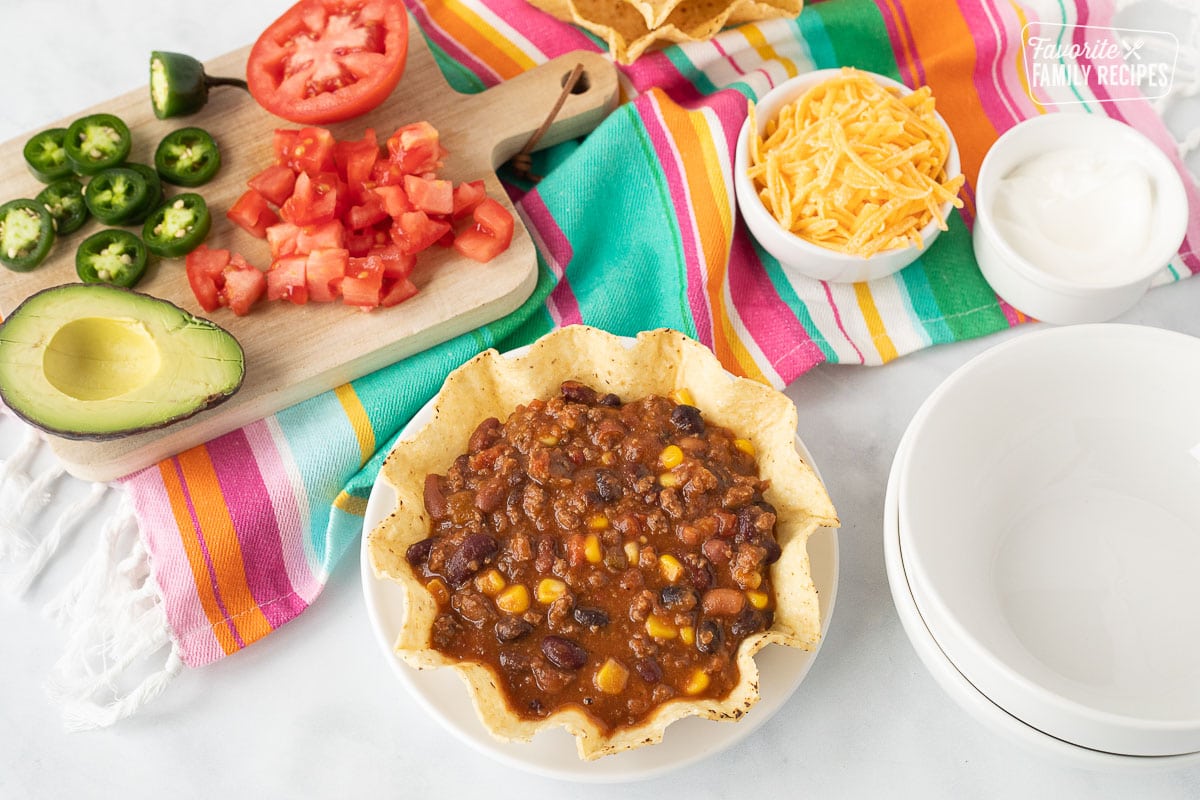 Mexican Chili in a tostado bowl with fixings on the side.