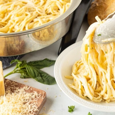 Tongs serving noodles on a plate for One Pot Creamy Garlic Noodles.