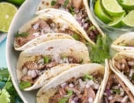 Platter of Steak Street Tacos with sliced lime wedges.