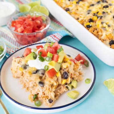 Slice of Mexican Chicken Casserole with sour cream, sliced avocado, green onions and tomatoes.