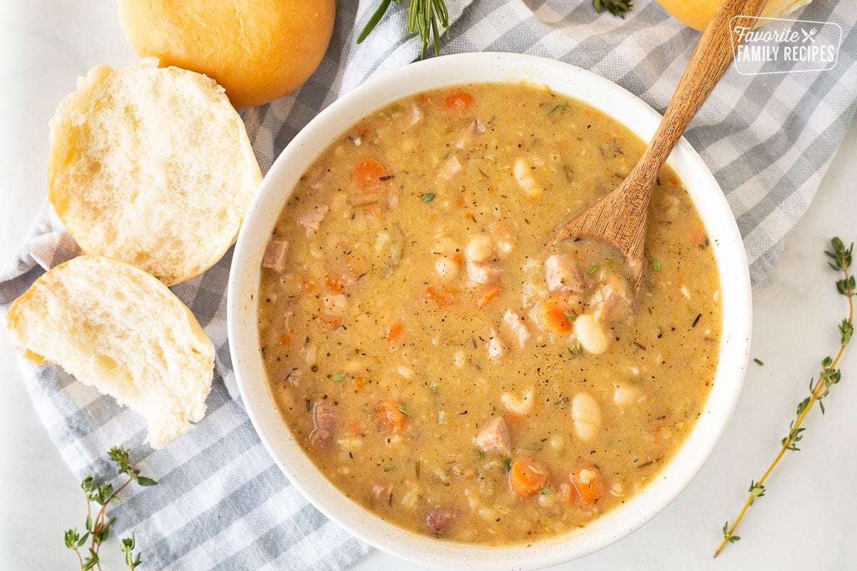 Ham and Bean Soup in a bowl with a spoon and rolls.