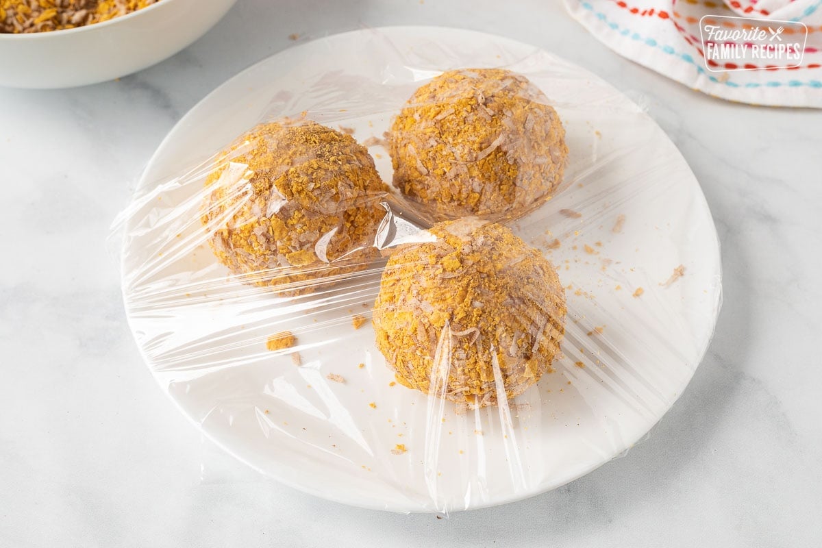 Three balls of Fried Ice Cream on a plate covered with plastic wrap.