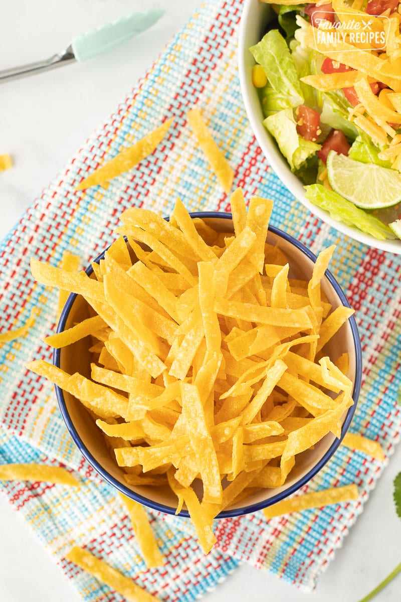 Bowl of Tortilla Strips next to a salad topped with Tortilla Strips.