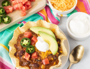 Mexican Chili in a tostada bowl with sour cream, avocado, jalapeños, cheese and tomatoes.