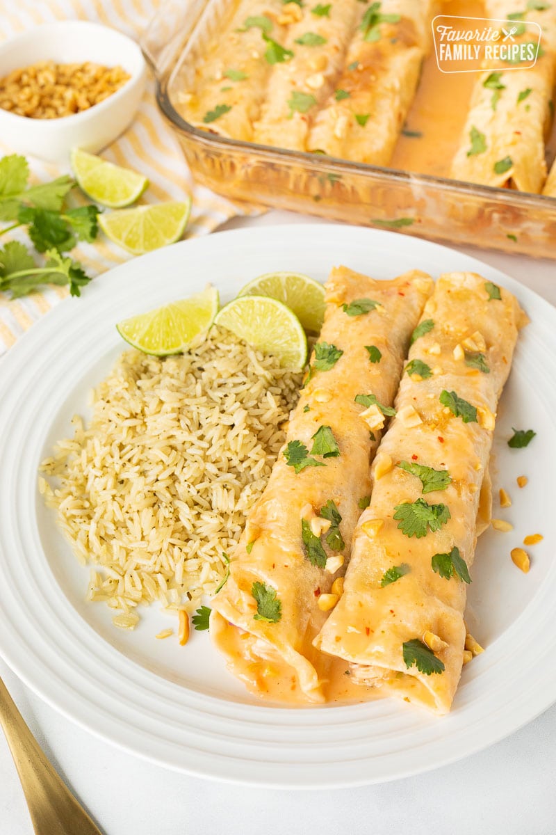 Two Thai Chicken Enchiladas on a plate with rice and limes.
