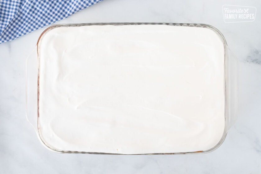 Glass rectangle dish with whipped topping layer for Banana Split Dessert.