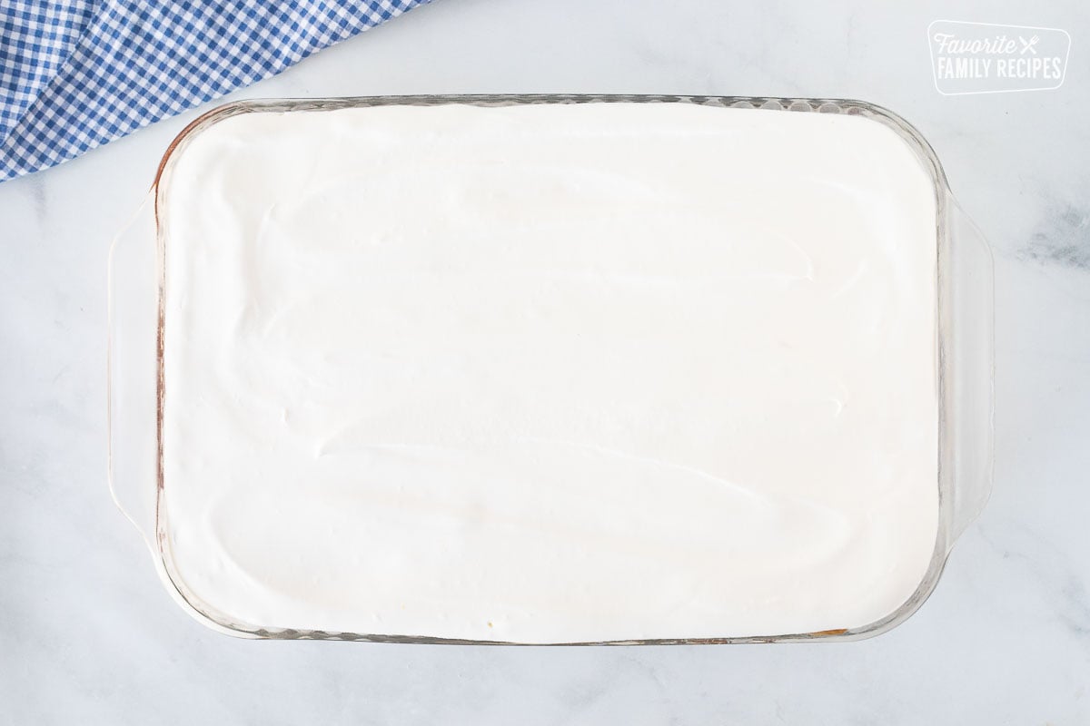 Glass rectangle dish with whipped topping layer for Banana Split Dessert.