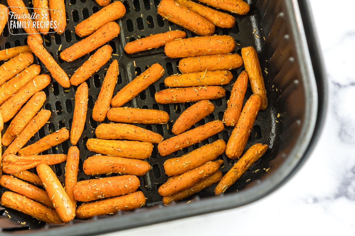 Cooked baby carrots in an air fryer basket.