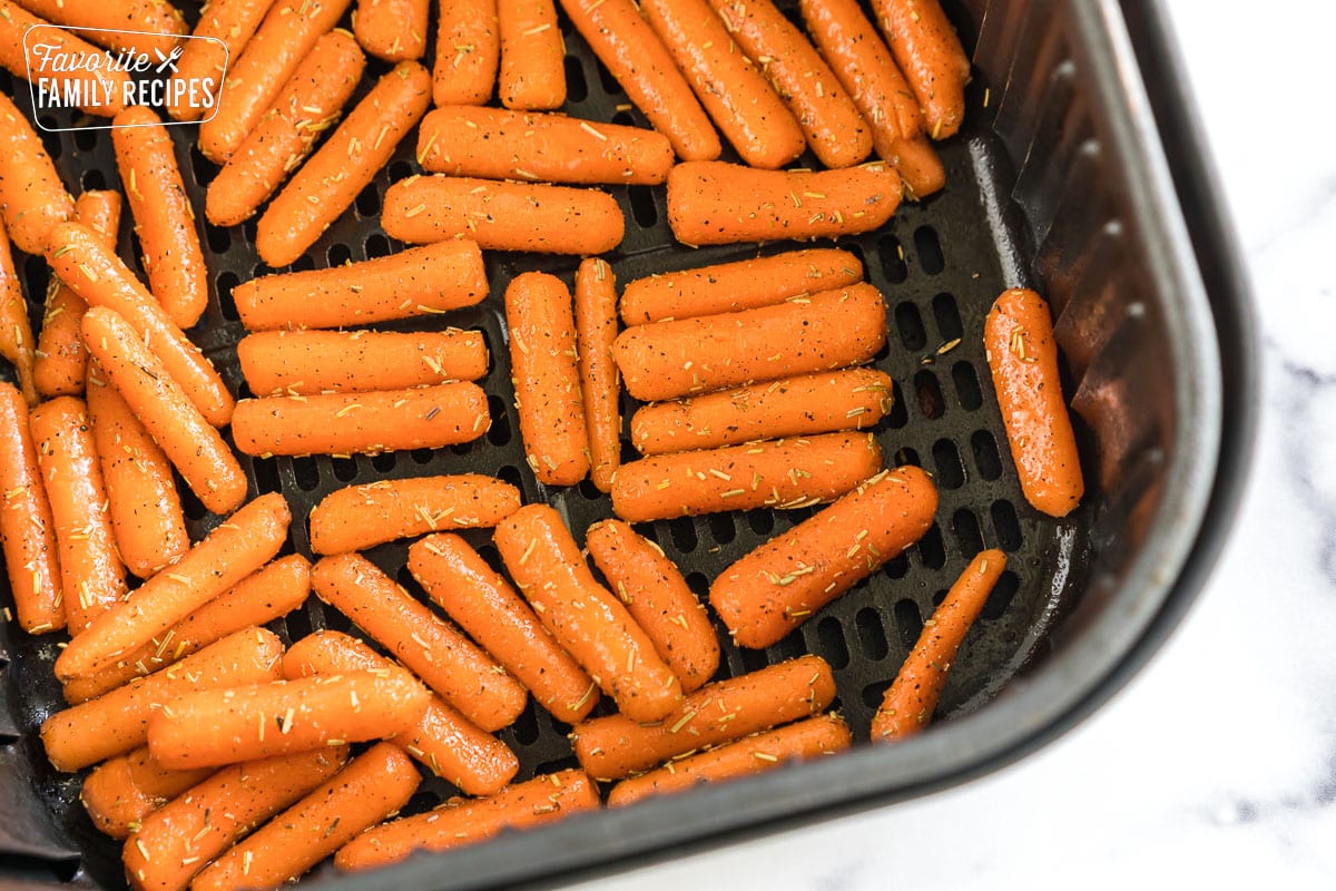 Uncooked seasoned baby carrots in an air fryer basket