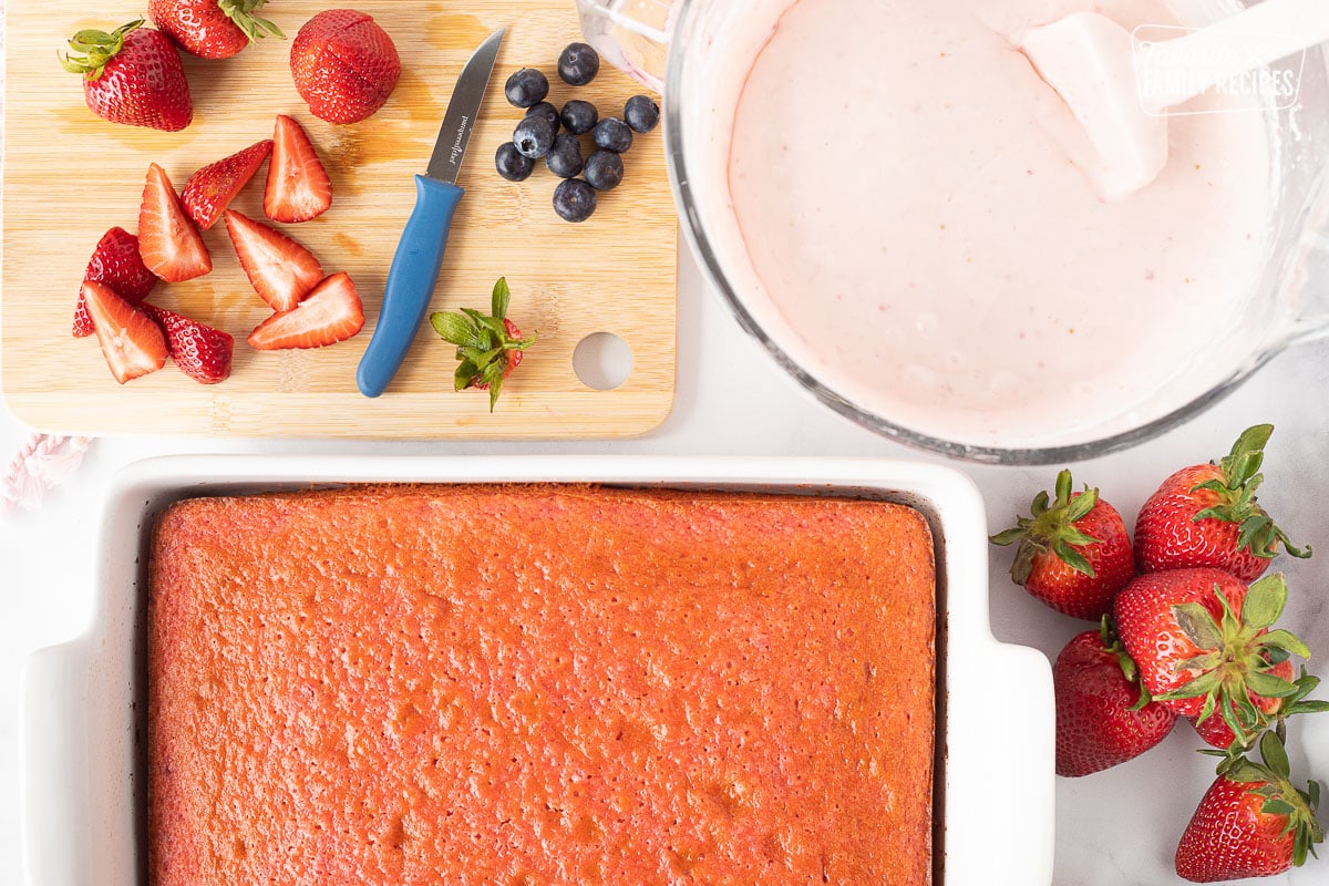 Baked Strawberry Cake, fresh strawberries, blueberries, with cutting board and frosting.