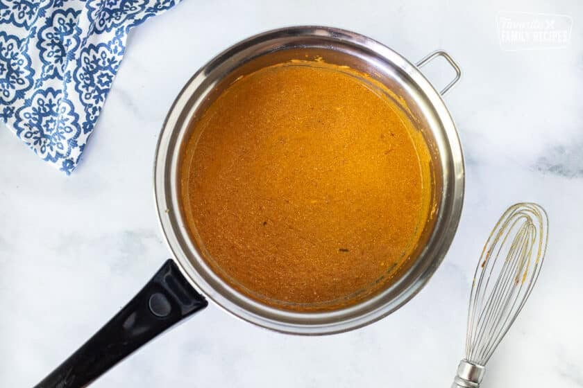 Pan of Chicken Korma base with no chicken. Whisk on the side.