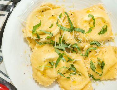 A bowl of homemade ravioli with olive oil and basil over the top