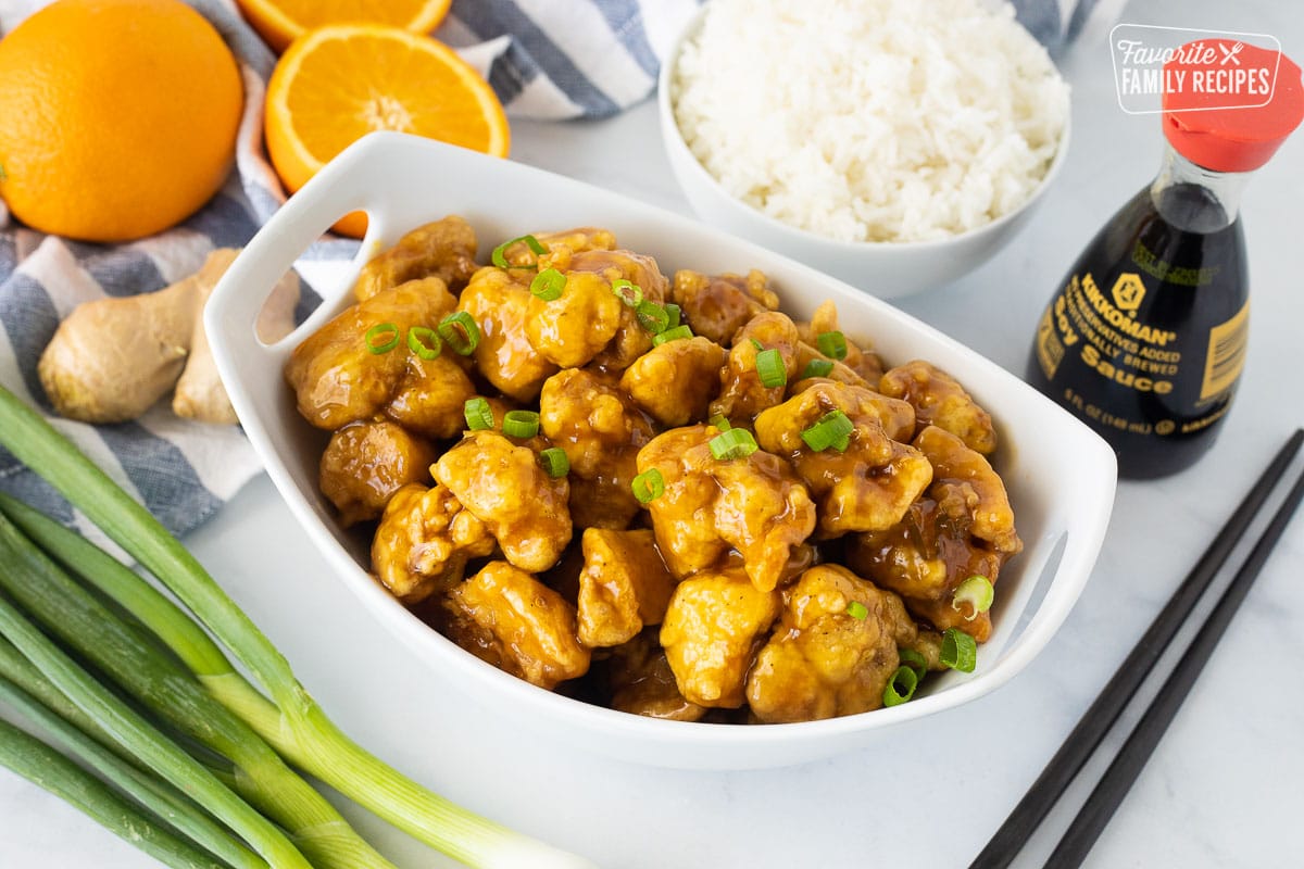 Bowl of Orange Chicken garnished with sliced green onions.