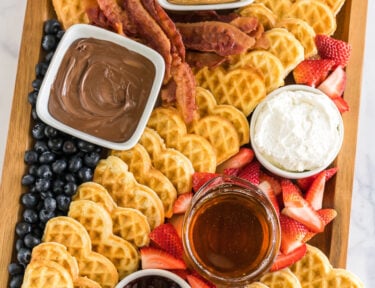 A breakfast charcuterie board with waffles and waffle toppings