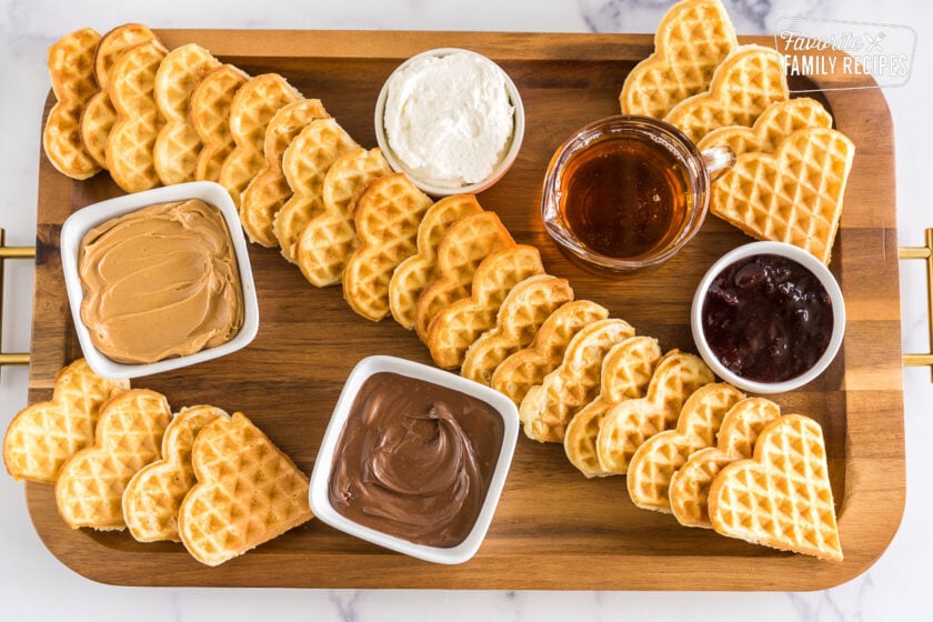 a wooden serving board with waffles and waffle spreads
