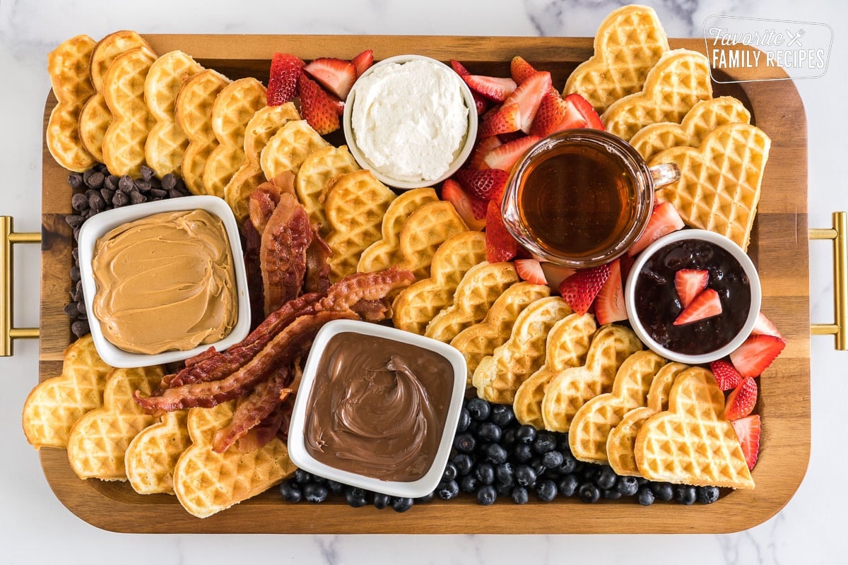 A breakfast charcuterie board with waffles and waffle toppings.