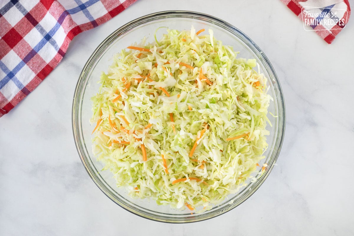 Glass bowl of shredded green cabbage and carrots for Coleslaw.