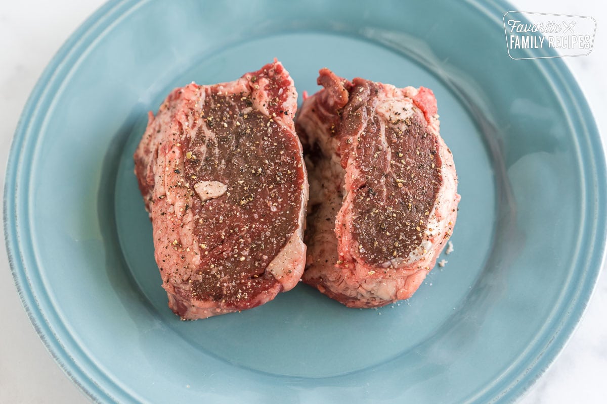 two filets on a plate seasoned with salt and pepper.