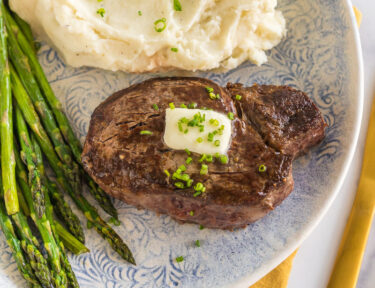 Cast iron filet mignon on a plate with mashed potatoes and asparagus