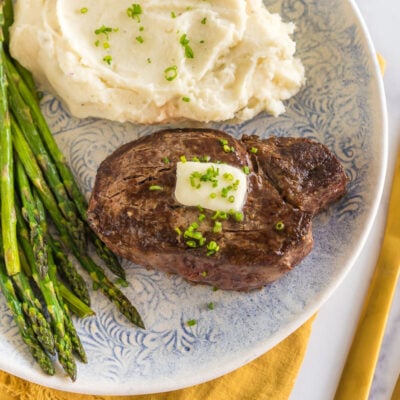 Cast iron filet mignon on a plate with mashed potatoes and asparagus