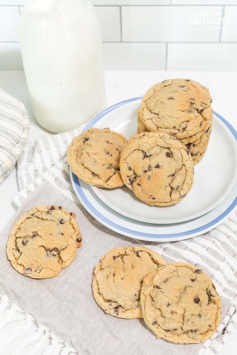 Chocolate chip cookies on a plate next to a pitcher of milk