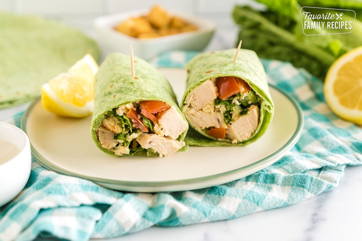 A chicken caesar wrap on a plate cut in half