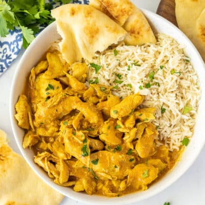 Large bowl of Chicken Korma with rice and ripped Naan Bread.