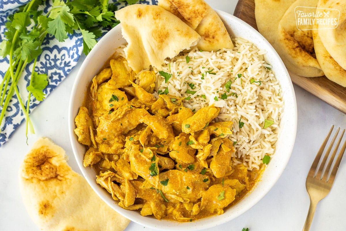Large bowl of Chicken Korma with rice and ripped Naan Bread.