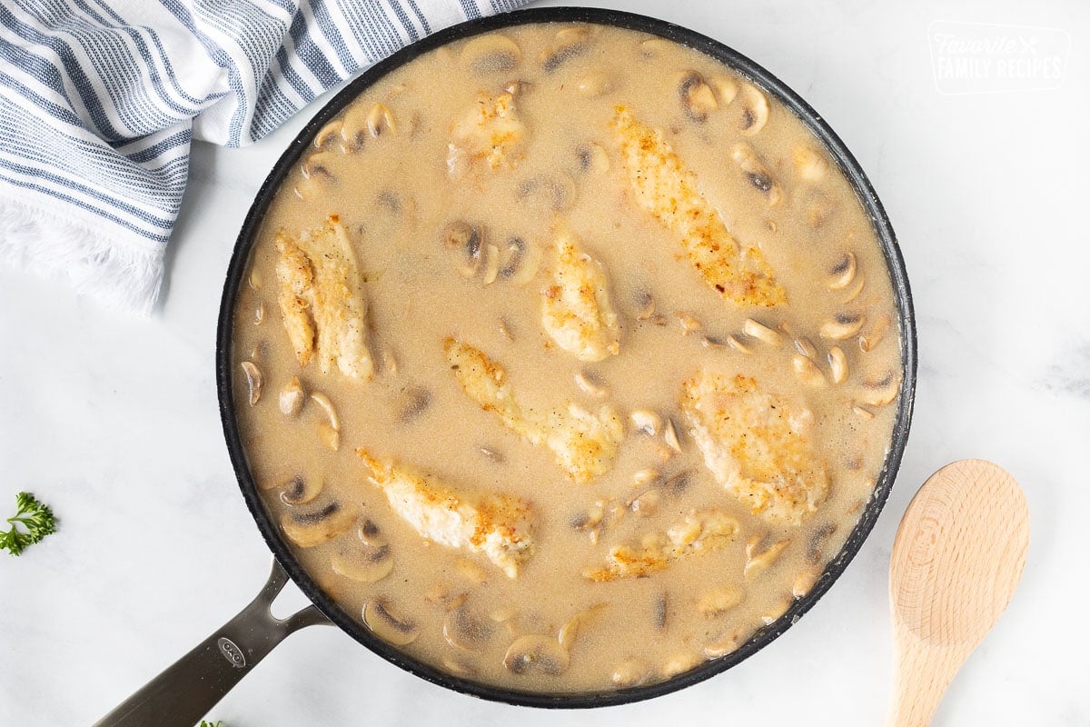 Skillet with chicken pieces in sauce for Chicken Marsala.