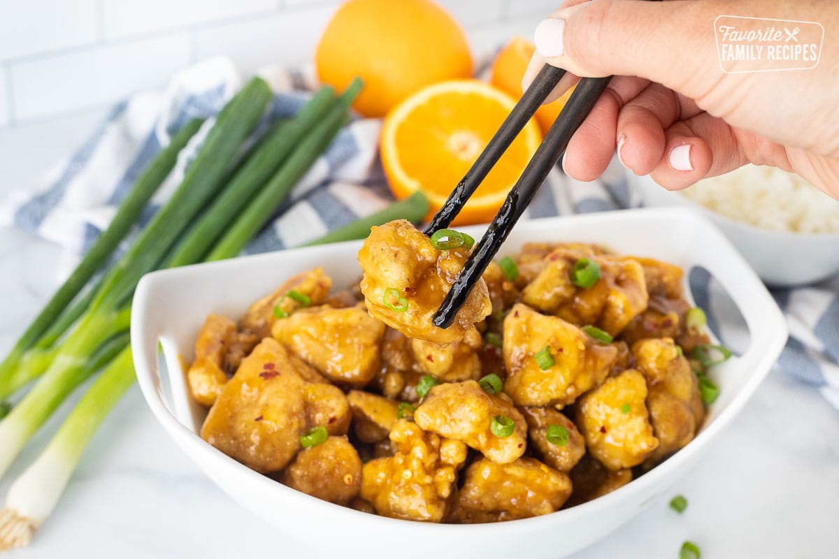 Chopsticks grabbing a piece of Orange Chicken.