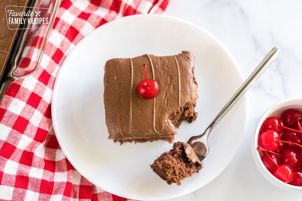 Coca cola cake on a plate topped with a maraschino cherry