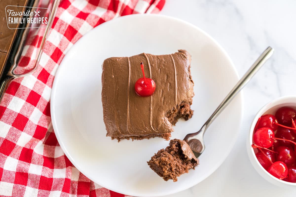 Coca cola cake on a plate topped with a maraschino cherry.