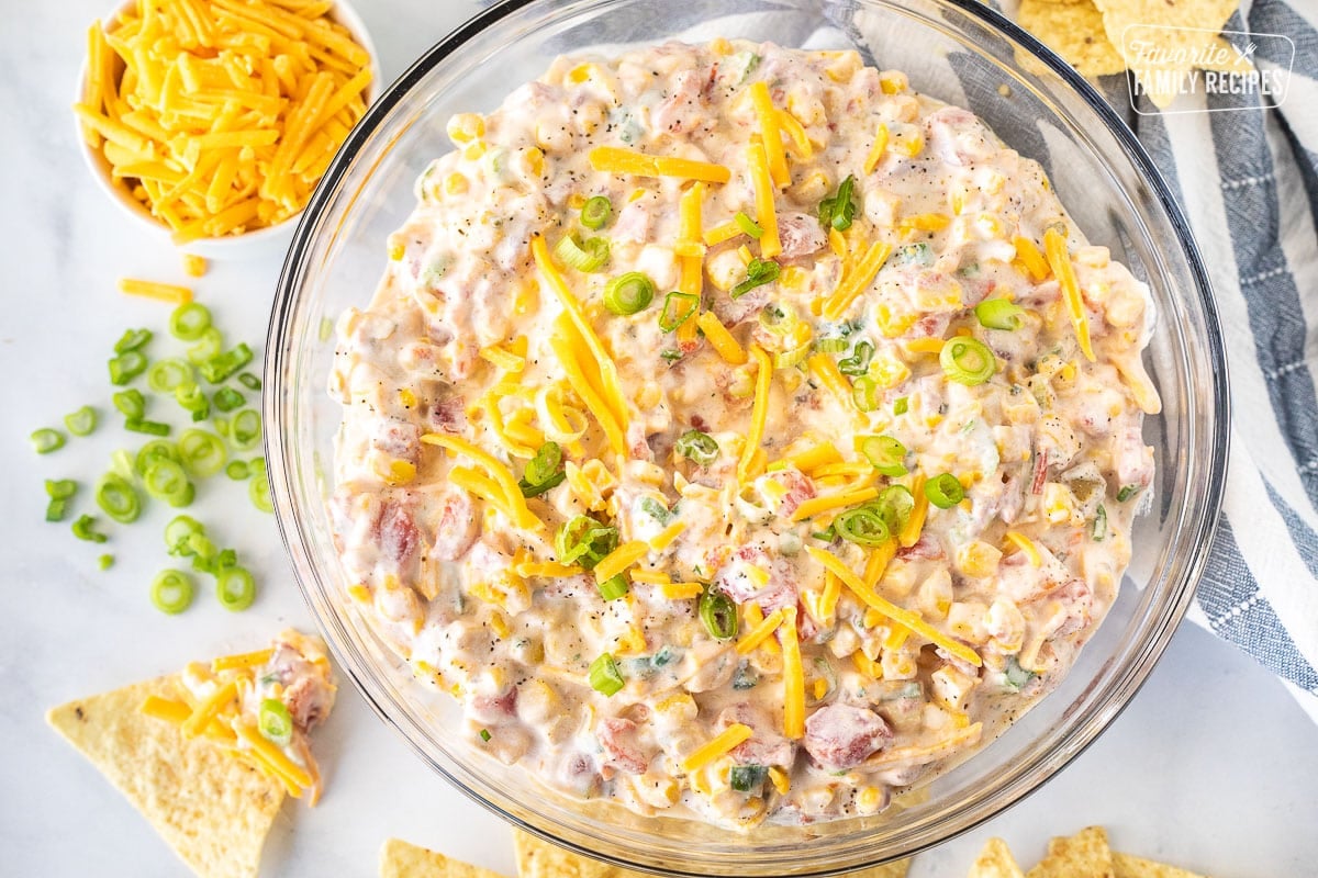 Bowl of Creamy Corn Dip next to a tortilla chip with Creamy Corn Dip.