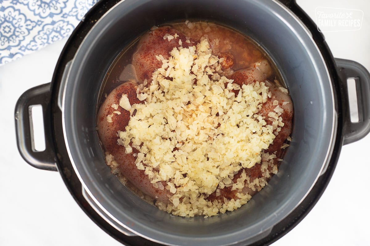 Chicken, spices, onions and broth in crockpot for Honey Lime Chicken Enchiladas.