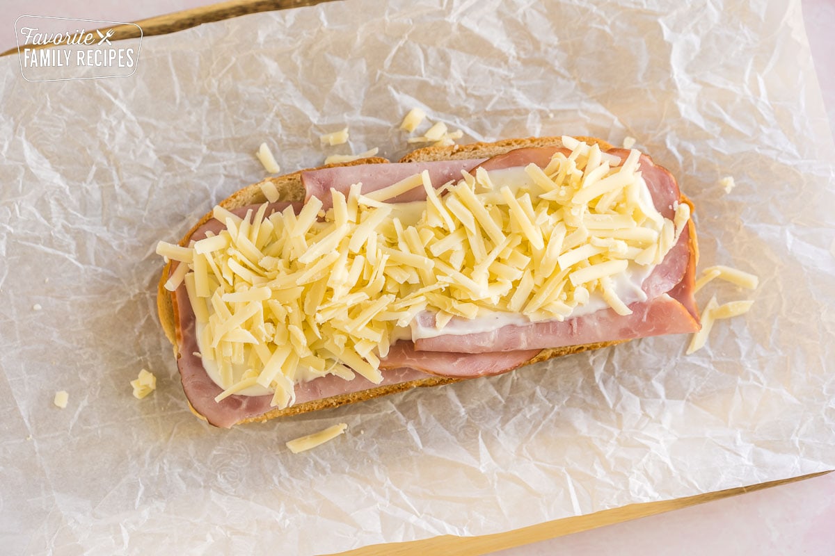 a slice of bread topped with slices of ham, bechamel, and shredded cheese