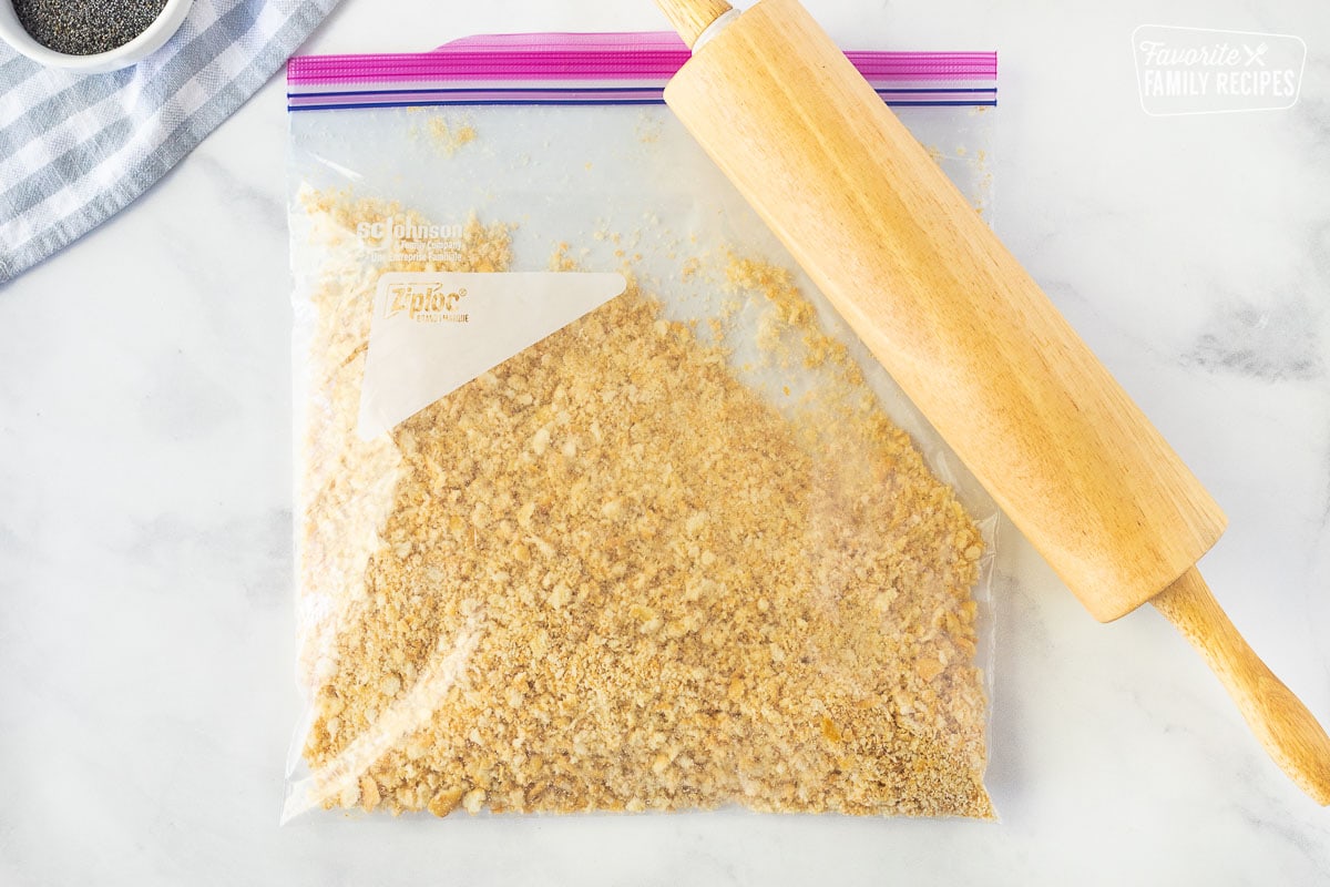 Ziplock back of crushed Ritz crackers with a rolling pin for Poppy Seed Chicken.