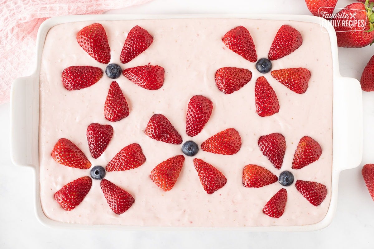 Decorated Fresh Strawberry Cake with sliced strawberries and blueberries shaped like flowers.