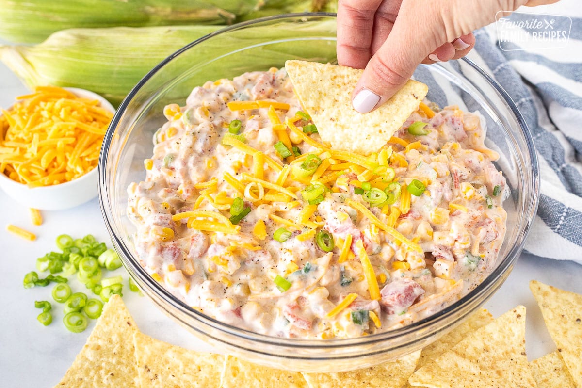 Dipping a tortilla chip in a bowl of Creamy Corn Dip.