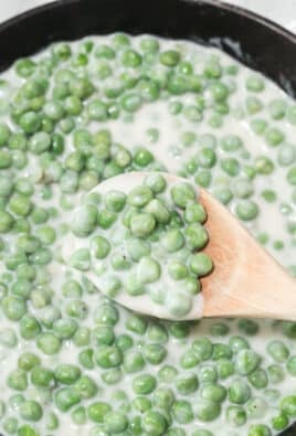 A wooden spoon with a scoop of creamed peas