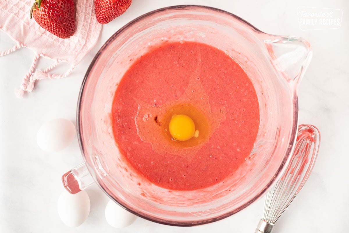 Mixing bowl with batter and an egg for Fresh Strawberry Cake.