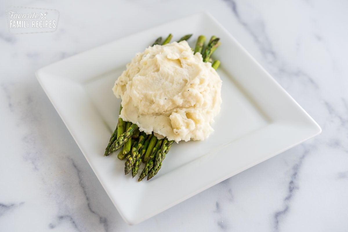 Asparagus topped with mashed potatoes on a plate