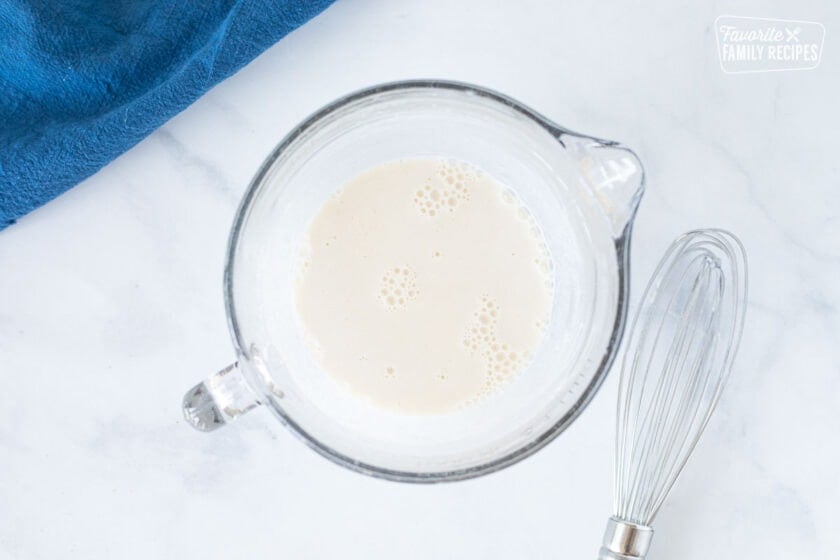 Mixing bowl with flour and milk next to a whisk for Seafood Chowder.