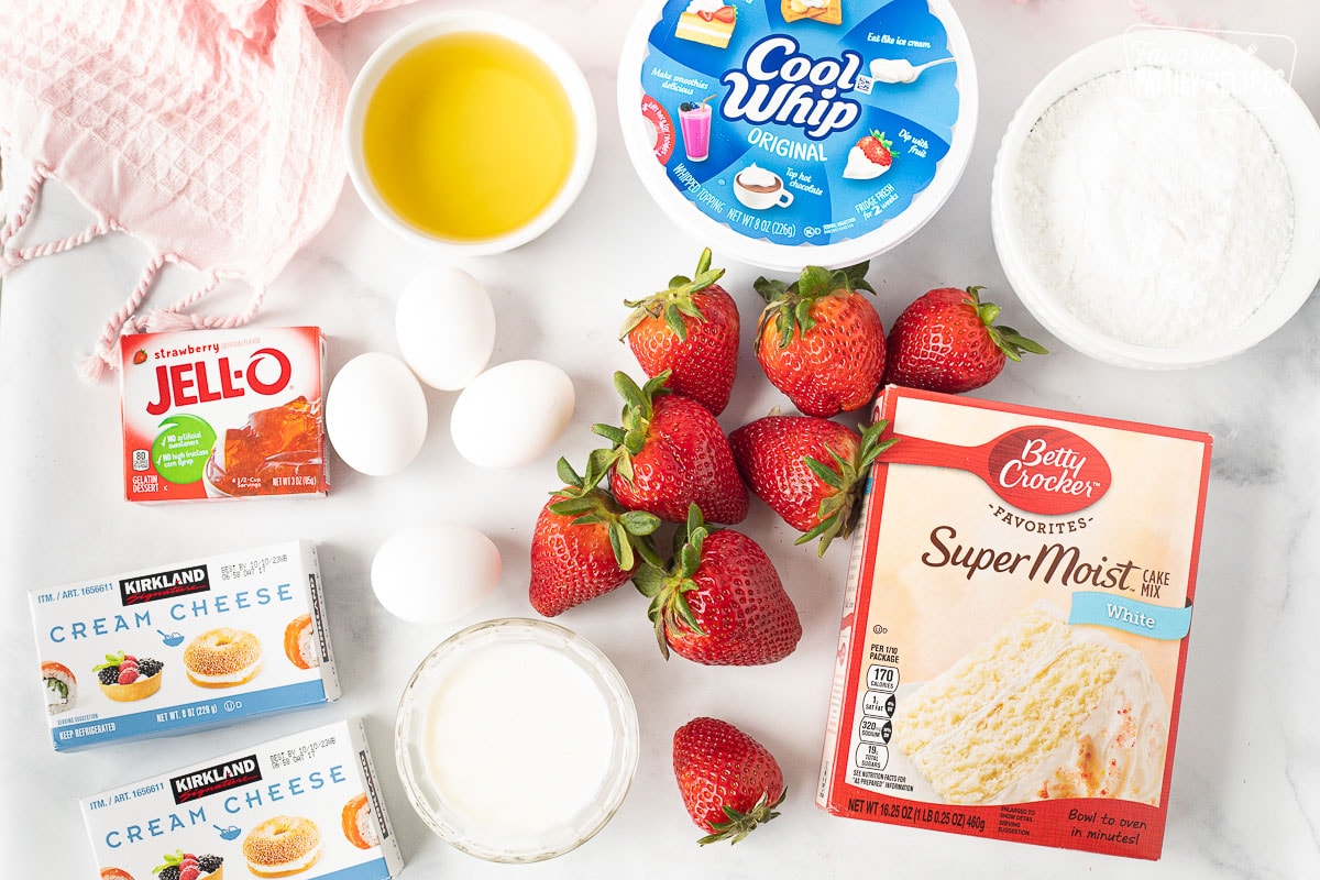 Ingredients to make Fresh Strawberry Cake including strawberry jello, oil, cool whip, powdered sugar, cream cheese, milk, eggs, white cake mix and fresh strawberries.