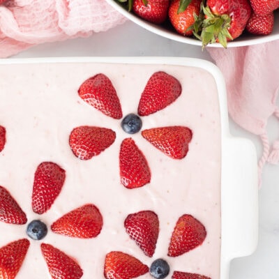 Bowl of fresh strawberries and a baking dish with decorated Fresh Strawberry Cake.