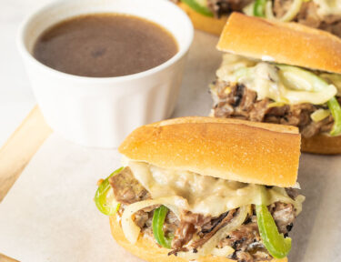 Half of a Philly Cheesesteak with a cup of au jus.